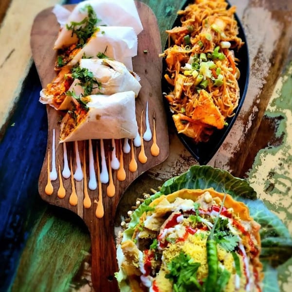 Three Indian dishes: chicken wraps, noodles with paneer, and a chaat in a crispy shell.
