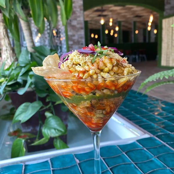 A colorful Indian Bhel Puri dish, layered with sauces and toppings, served in a martini glass.